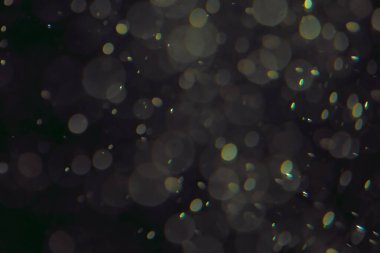 Koyu bir arkaplanda farklı boyut ve renklerde odaklanmış bokeh ışıkları.