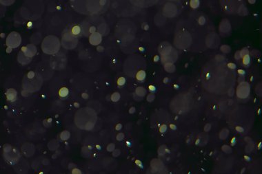 Koyu bir arkaplanda farklı boyut ve renklerde odaklanmış bokeh ışıkları.