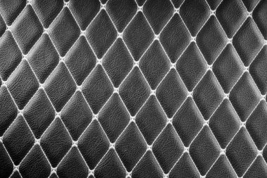 Elmas şekilli dikişli siyah deri bir yüzeye yakın plan. Derinin derin, zengin rengi ve karmaşık dikişler lüks ve sofistike bir görünüm yaratıyor.