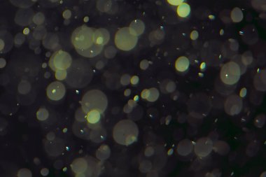 Koyu bir arkaplanda farklı boyut ve renklerde odaklanmış bokeh ışıkları.