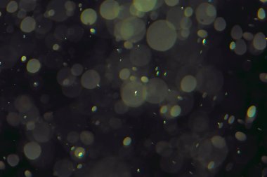 Koyu bir arkaplanda farklı boyut ve renklerde odaklanmış bokeh ışıkları.