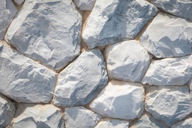 Düzensiz şekilli gri ve beyaz taşlardan oluşan doğal bir taş duvarın yakın çekimi. Özgeçmiş, doku veya tasarım ilhamı için ideal.