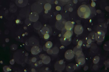 Koyu bir arkaplanda farklı boyut ve renklerde odaklanmış bokeh ışıkları.