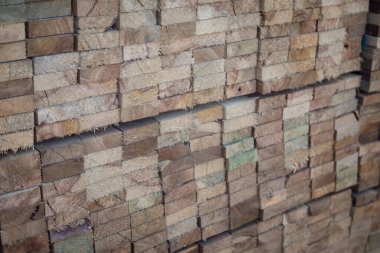 Kereste deposunda istiflenmiş ahşap kalaslar, çeşitli gölgeler ve dokular, düzenli bir şekilde düzenlenmiş..