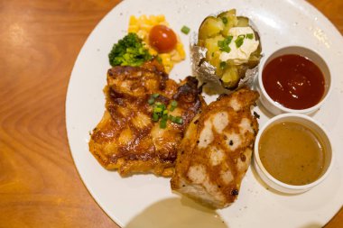 Izgara domuz bifteği, patates püresi ve sebzeyle servis edilir.