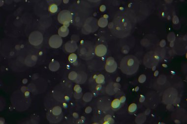 Koyu bir arkaplanda farklı boyut ve renklerde odaklanmış bokeh ışıkları.