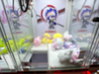 Pembe pelüş oyuncaklarla dolu renkli bir pençe makinesi oyuncuları eğlenceli bir oyun salonunda şanslarını denemeye davet ediyor..