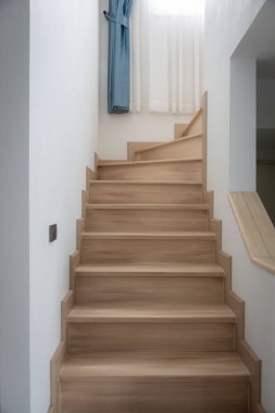 Modern, açık renkli ahşap bir merdiven çağdaş bir evde, temiz çizgiler ve minimalist tasarım sergiliyor..