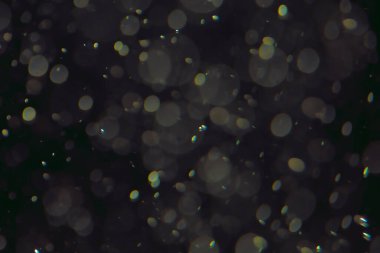 Koyu bir arkaplanda farklı boyut ve renklerde odaklanmış bokeh ışıkları.