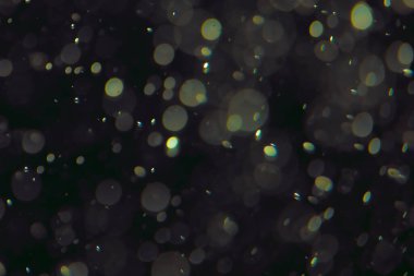 Koyu bir arkaplanda farklı boyut ve renklerde odaklanmış bokeh ışıkları.