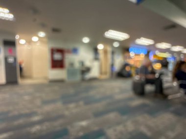 Havaalanının iç kısmının bulanık görüntüsü, hafif ışıklandırma, oturma alanları ve sakin, bastırılmış bir atmosferi var..