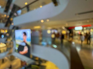 Hareketli bir alışveriş merkezinin bulanık görüntüsü modern bir perakende satış ortamının canlı atmosferini yakalıyor. İnsanlar alışveriş yaparken görülüyor.
