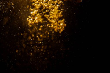Soyut bulanık altın bokeh ışıkları koyu bir arkaplan karşısında dramatik ve şenlikli bir atmosfer yaratır.