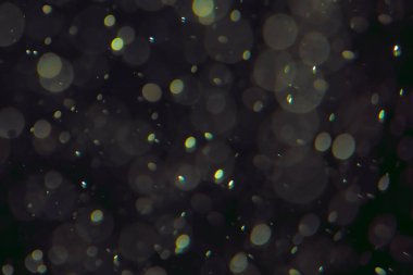 Koyu bir arkaplanda farklı boyut ve renklerde odaklanmış bokeh ışıkları.