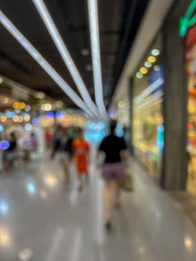 Hareketli bir alışveriş merkezinin bulanık görüntüsü modern bir perakende satış ortamının canlı atmosferini yakalıyor. İnsanlar yürürken, alışveriş yaparken ve eğlenirken görülürler.