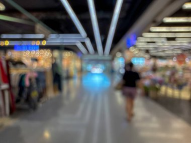 Hareketli bir alışveriş merkezinin bulanık görüntüsü modern bir perakende satış ortamının canlı atmosferini yakalıyor. İnsanlar yürürken, alışveriş yaparken ve eğlenirken görülürler.