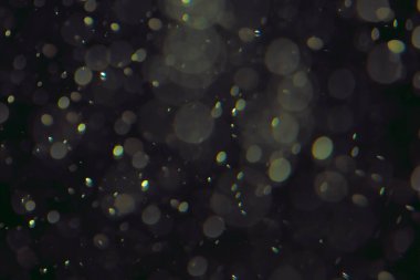 Koyu bir arkaplanda farklı boyut ve renklerde odaklanmış bokeh ışıkları.