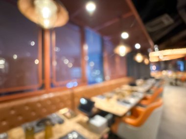 Sıcak ışıklandırması ve şık mobilyaları olan çağdaş bir restoranın bulanık görüntüsü..