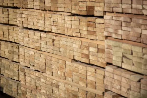 Kereste deposunda istiflenmiş ahşap kalaslar, çeşitli gölgeler ve dokular, düzenli bir şekilde düzenlenmiş..