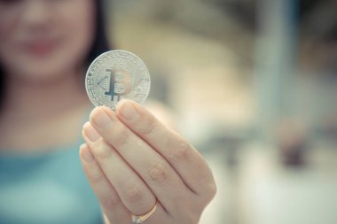 Elinde Bitcoin dijital para ve arka planı bulanık kripto para tutan güzel bir kadın. Kaşsız Toplum kavramı Web Sanal Para Madenciliği.