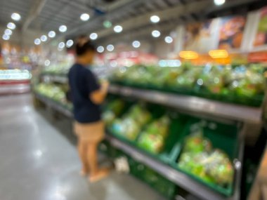 Raflarda çeşitli taze meyve ve sebzelerin sergilendiği bir market üretim bölümünün bulanık görüntüsü. Resim ürünün canlı renklerini ve dokularını yakalar