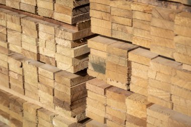 Kereste deposunda istiflenmiş ahşap kalaslar, çeşitli gölgeler ve dokular, düzenli bir şekilde düzenlenmiş..