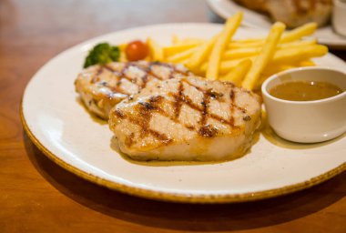 Kızarmış domuz bifteği, yanında patates kızartması ve sebze.