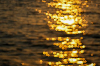 Bulanık bokeh etkisi soyut görüntü güneş ışığının su üzerindeki altın yansımalarını yakalıyor, rüya gibi bir görüntü yaratıyor.