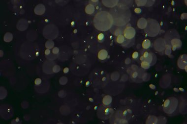 Koyu bir arkaplanda farklı boyut ve renklerde odaklanmış bokeh ışıkları.