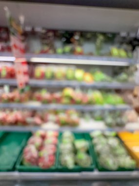 Raflarda çeşitli taze meyve ve sebzelerin sergilendiği bir market üretim bölümünün bulanık görüntüsü. Resim ürünün canlı renklerini ve dokularını yakalar