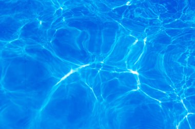 Güneş ışığı yansımalı berrak mavi havuz suyu soyut desenler ve dalgalanmalar yaratır.