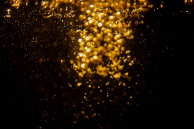 Soyut bulanık altın bokeh ışıkları koyu bir arkaplan karşısında dramatik ve şenlikli bir atmosfer yaratır.