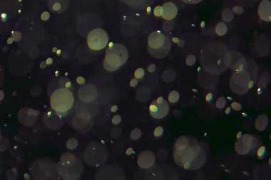 Koyu bir arkaplanda farklı boyut ve renklerde odaklanmış bokeh ışıkları.