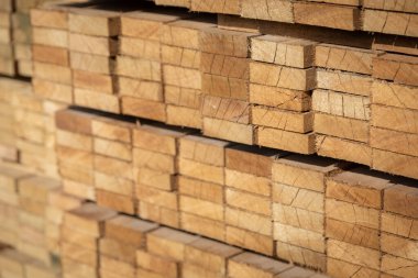 Kereste deposunda istiflenmiş ahşap kalaslar, çeşitli gölgeler ve dokular, düzenli bir şekilde düzenlenmiş..