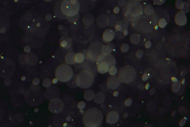 Koyu bir arkaplanda farklı boyut ve renklerde odaklanmış bokeh ışıkları.