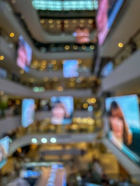 Hareketli bir alışveriş merkezinin bulanık görüntüsü modern bir perakende satış ortamının canlı atmosferini yakalıyor. İnsanlar alışveriş yaparken görülüyor.