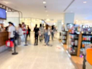 Hareketli bir alışveriş merkezinin bulanık görüntüsü modern bir perakende satış ortamının canlı atmosferini yakalıyor. İnsanlar alışveriş yaparken görülüyor.