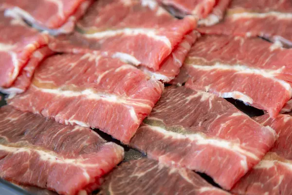 Çiğ et dilimlerinin karmaşık mermerlerini gösteren yakın plan bir fotoğraf. Parlak kırmızı renkler, beyaz yağ çizgileriyle çok güzel tezat oluşturuyor.