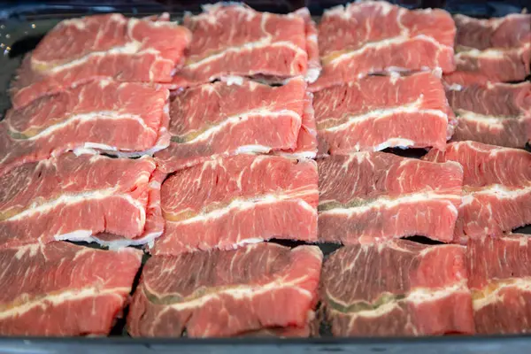 Çiğ et dilimlerinin karmaşık mermerlerini gösteren yakın plan bir fotoğraf. Parlak kırmızı renkler, beyaz yağ çizgileriyle çok güzel tezat oluşturuyor.