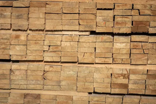 Kereste deposunda istiflenmiş ahşap kalaslar, çeşitli gölgeler ve dokular, düzenli bir şekilde düzenlenmiş..