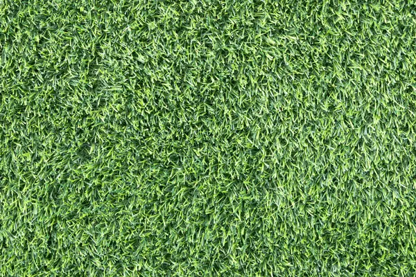 yemyeşil suni bir çimenliğe yakın çekim. Çimenlerin sentetik yaprakları mükemmel bir şekilde hizalanmış ve halı benzeri bir arka plan oluşturuyor.