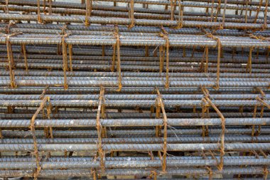 İnşaatta beton takviyesi için kullanılan çelik inşaat ızgarasına yakın çekim. Dayanıklılık için gerekli olan paslı çubuk deseni gösteriliyor.