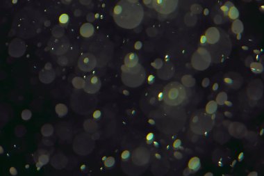 Koyu bir arkaplanda farklı boyut ve renklerde odaklanmış bokeh ışıkları.