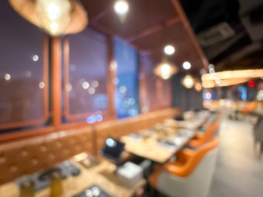 Sıcak ışıklandırması ve şık mobilyaları olan çağdaş bir restoranın bulanık görüntüsü..