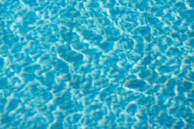 Işıldayan mavi su yüzeyine yakın çekim. Karmaşık ışık yansımaları dinamik dalgalanmalar yaratıyor. Ferahlatıcı ve yazlık bir ortam yaratıyor..