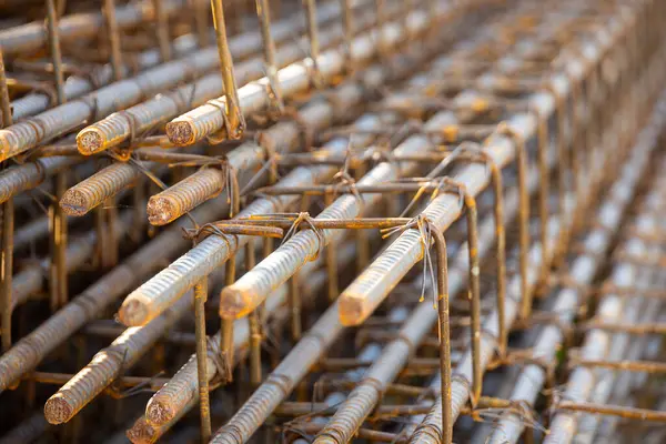 İnşaatta beton takviyesi için kullanılan çelik inşaat ızgarasına yakın çekim. Dayanıklılık için gerekli olan paslı çubuk deseni gösteriliyor.