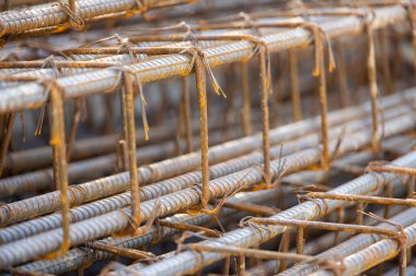 İnşaatta beton takviyesi için kullanılan çelik inşaat ızgarasına yakın çekim. Dayanıklılık için gerekli olan paslı çubuk deseni gösteriliyor.