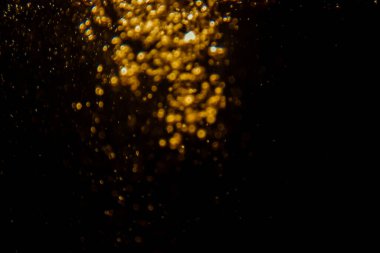 Soyut bulanık altın bokeh ışıkları koyu bir arkaplan karşısında dramatik ve şenlikli bir atmosfer yaratır.