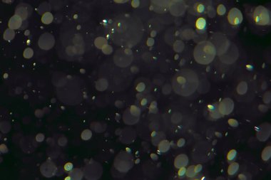 Koyu bir arkaplanda farklı boyut ve renklerde odaklanmış bokeh ışıkları.
