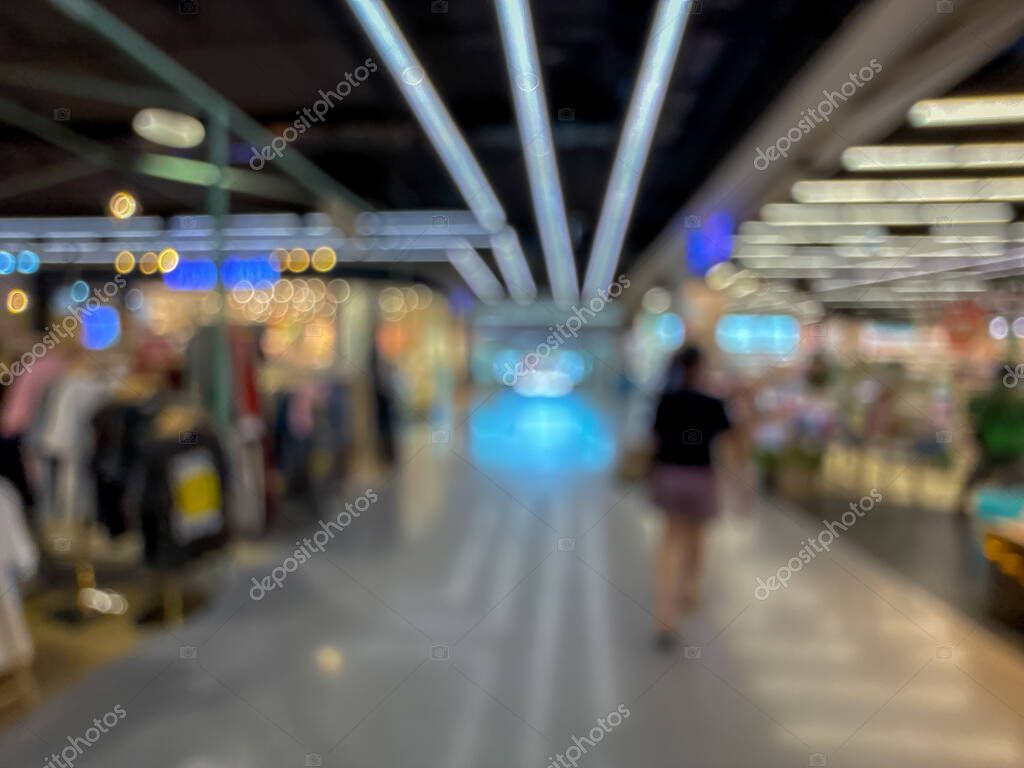 Blurred image of a bustling shopping mall, capturing the vibrant atmosphere of a modern retail environment. People are seen walking, shopping, and enjoying